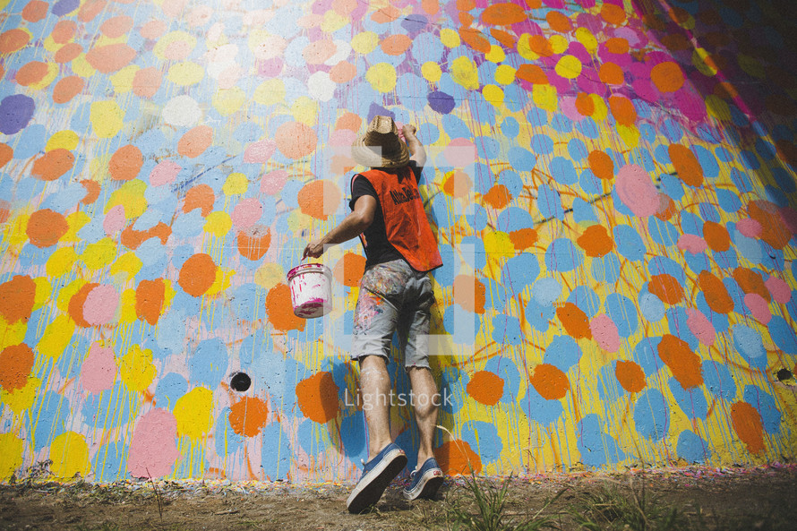 man painting abstract art at on a wall 