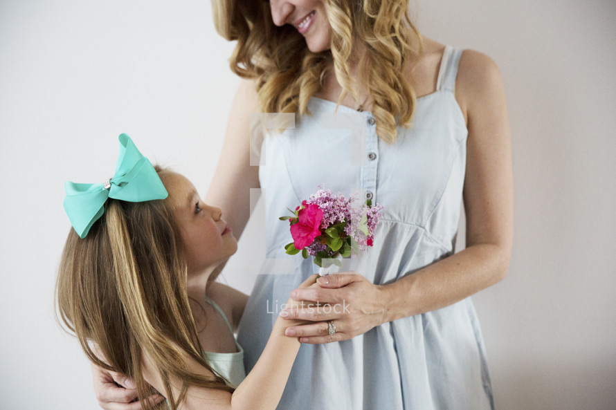 A young girl giving her mother a bouquet of flowers.