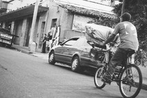 man on a bicycle , carrying a large basket on the front going doing a street