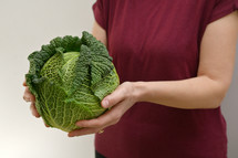 Woman holding green fresh organic savoy cabbage 