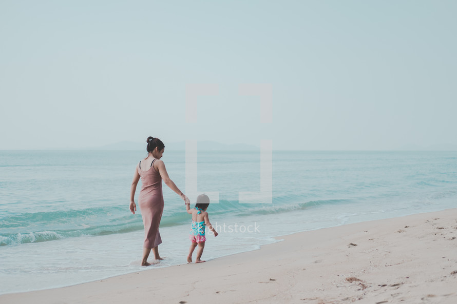 mother and child walking on a beach 
