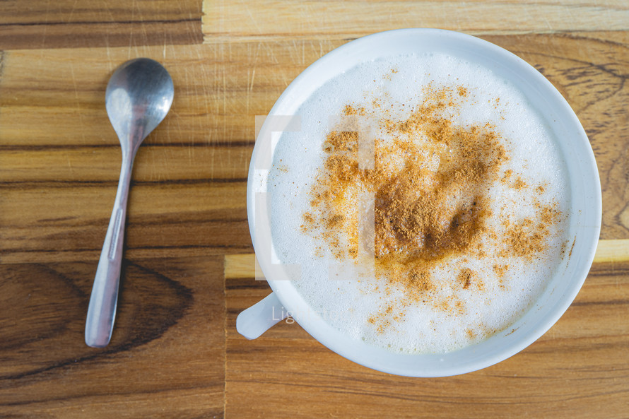 Delicious home made Cappuccino, in a white cup, on a wooden table. Home made Coffee.