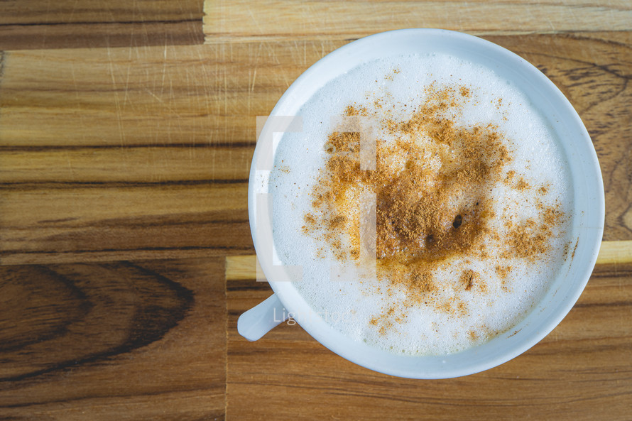 Delicious home made Cappuccino, in a white cup, on a wooden table. Home made Coffee.