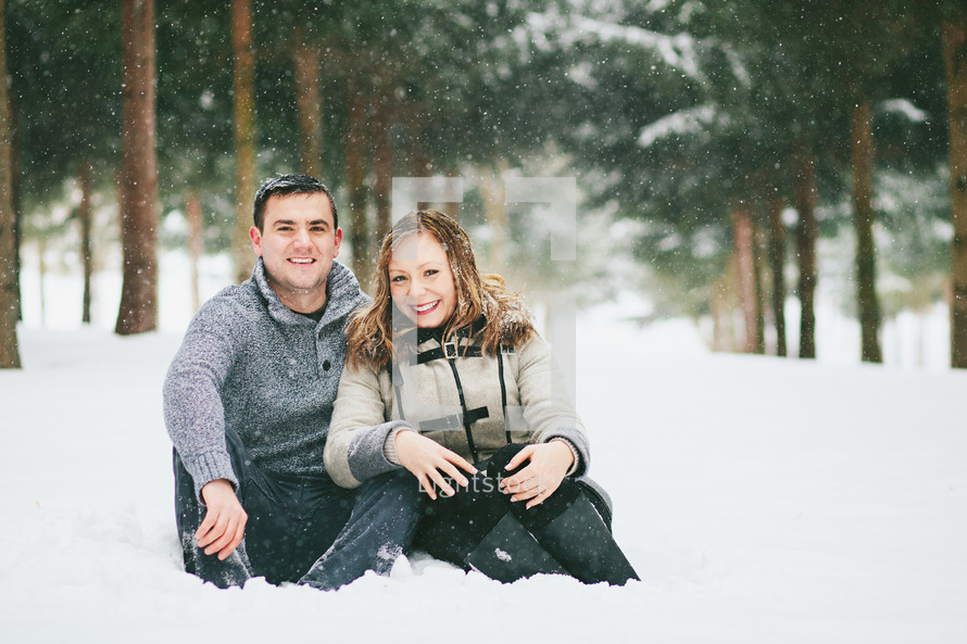 a couple sitting in the snow 