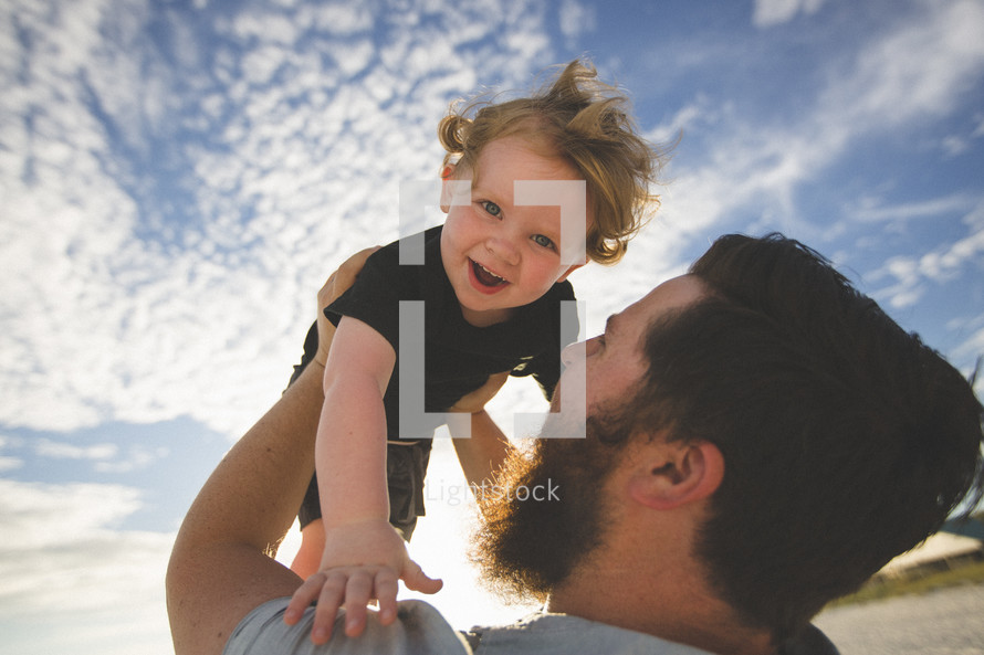 man holding his toddler son in the air 