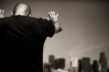 A man praying over a city - hands raised