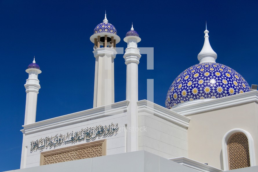 White Islamic Mosque with blue dome against blue sky 