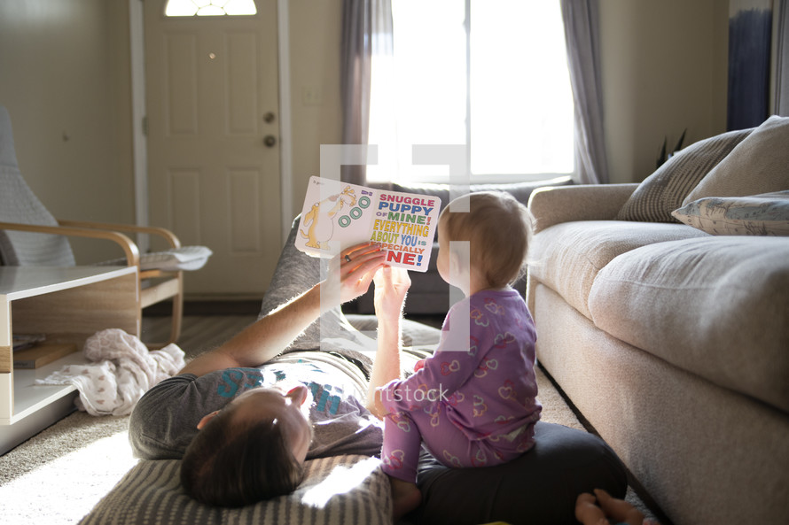 father reading a book to his toddler daughter 