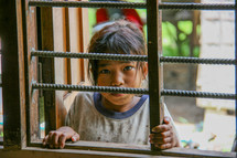 little girl looking through a window in Cambodia 