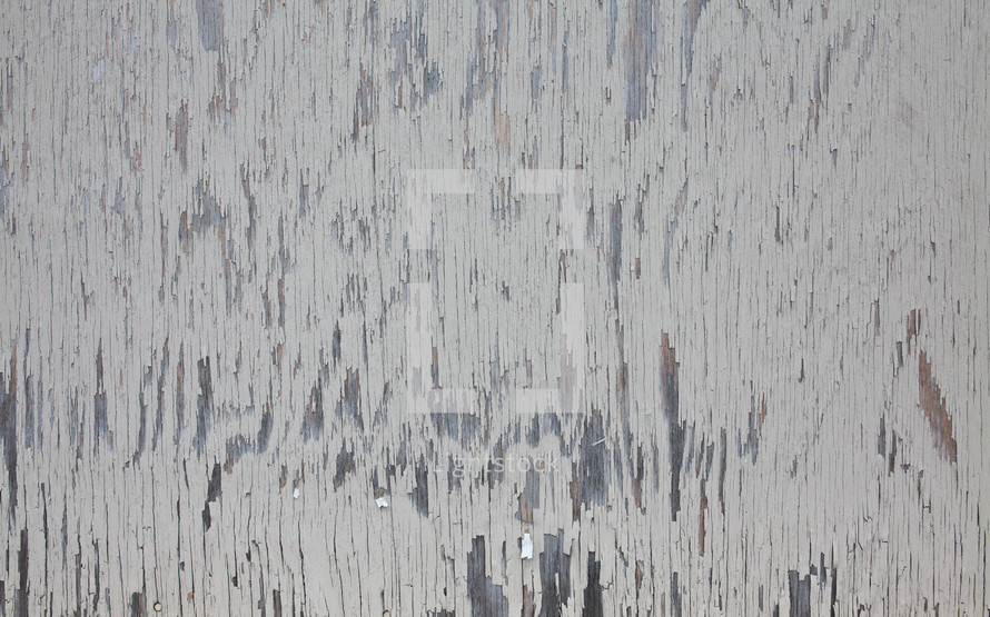 A wood surface with peeling white paint.