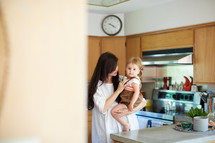 a mother holding her daughter in a kitchen 
