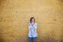 a woman standing in front of a yellow brick wall 