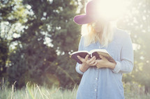 woman standing reading outdoors under intense sunlight 