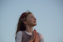 A little girl looking up to God with praying hands, child of god, hopeful 