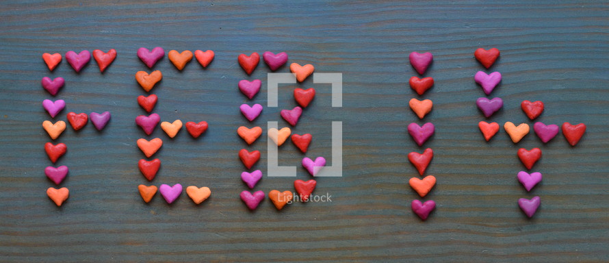 The date FEB 14 for February 14th written with many little colorful clay hearts on cyan wooden background 
