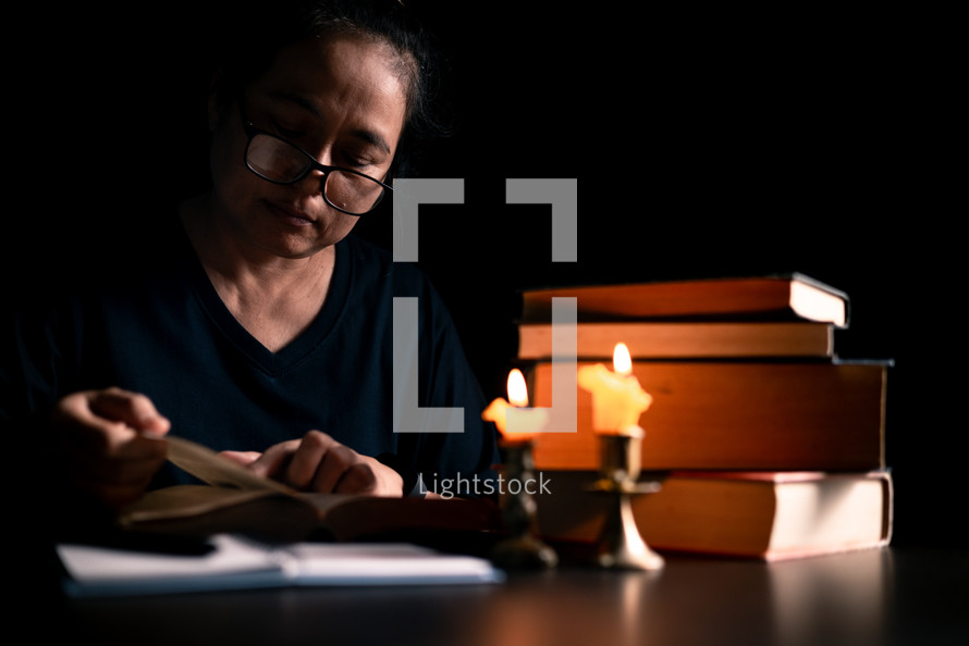 Bible and candlelight with studying woman