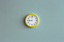 A yellow wall clock on a blue wall.