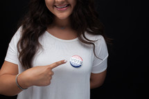 woman pointing to a vote pin 