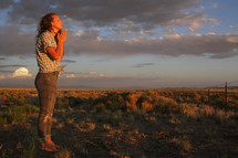 a girl praying outdoors at sunset 