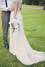 torso of a bride and groom standing in grass 