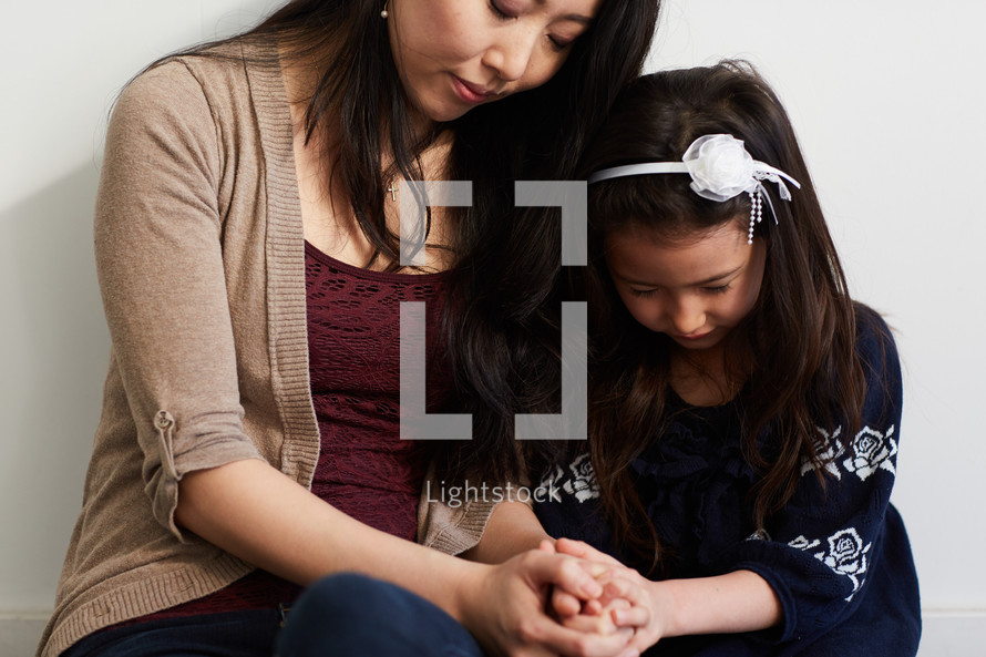 mother and daughter in studio praying 