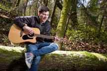 man playing a guitar and singing in a forest