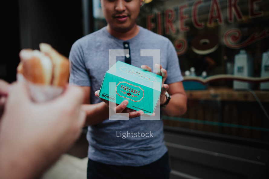 A man holding a box of cupcakes.