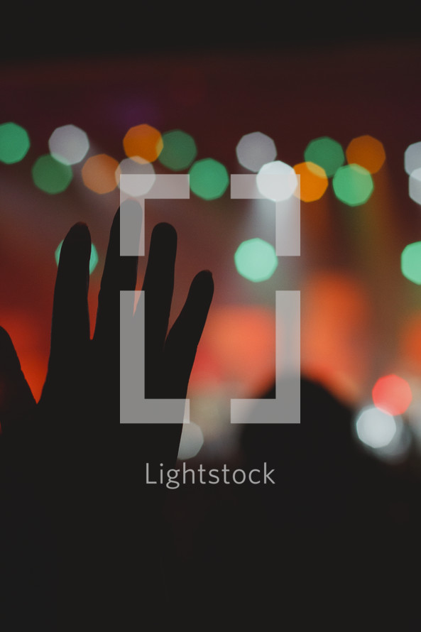 raised hand silhouette and bokeh lights 