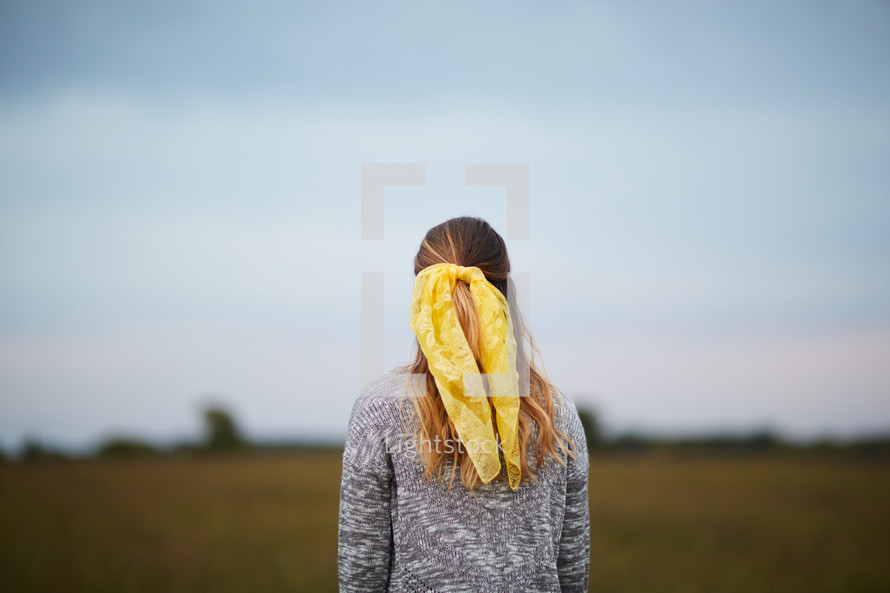 a woman in a sweater standing in a field 