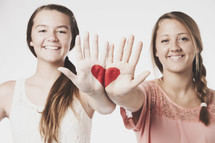 Two girls with a heart painted on their hands.
