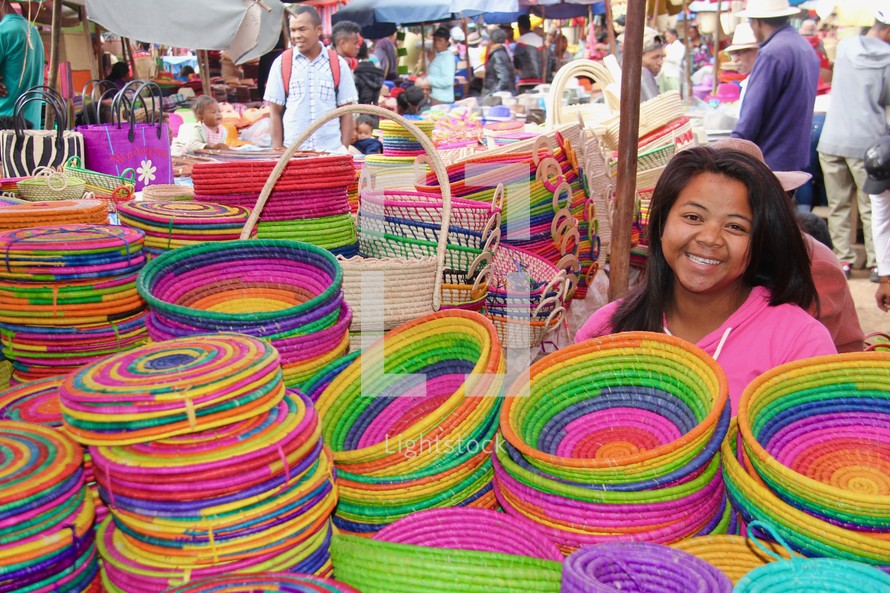 a woman in a market selling colorful baskets 
