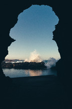 view of waves crashing into rocks from the mouth of a cave 