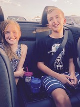 children riding in the back seat of a convertible on a road trip 