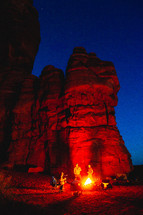 campfire beside red rocks cliffs at night 