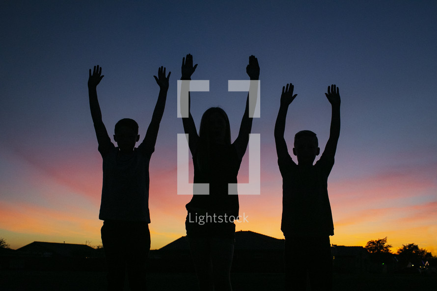 silhouettes of children with hands raised 