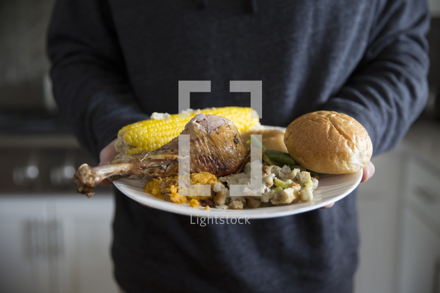 A person holding a plate full of food.