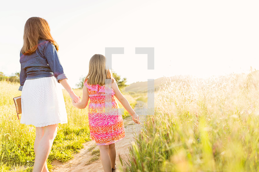 mother and daughter walking holding hands carrying a Bible