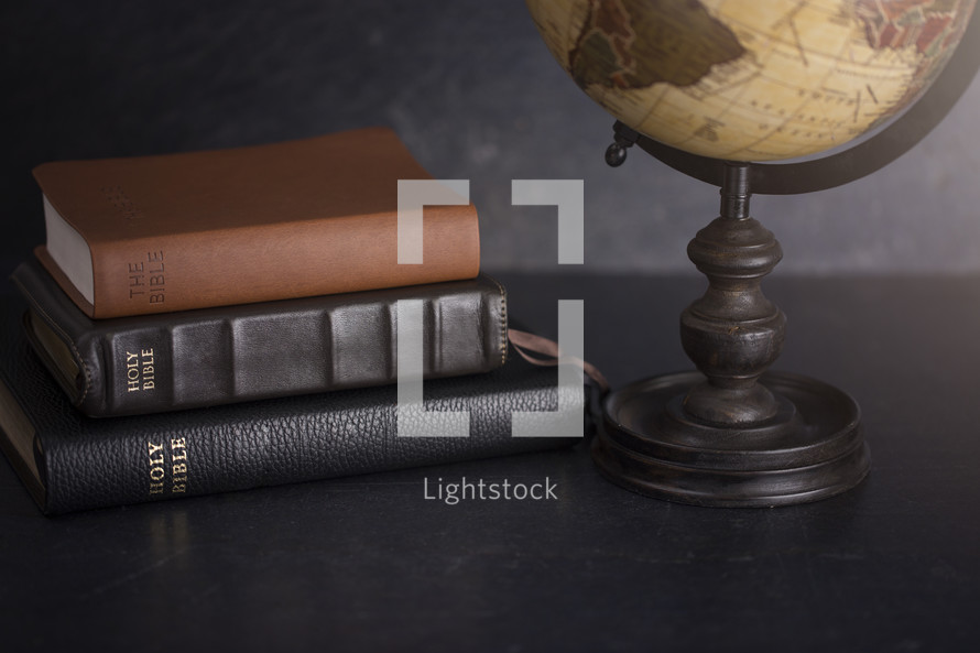 Stack of Bibles and a Globe on a Dark Background