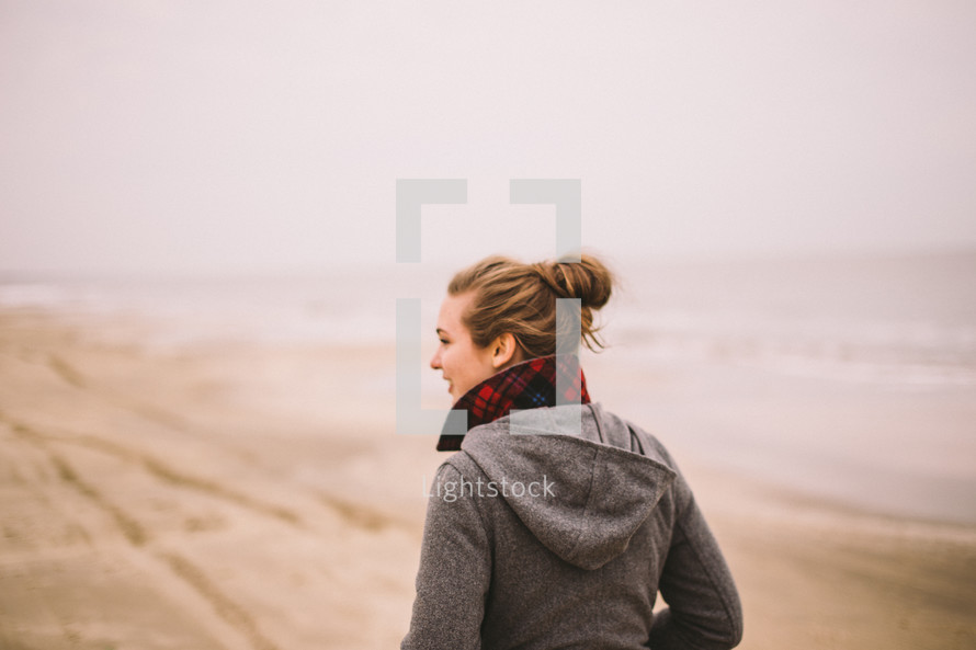 A young woman walks along a beach.