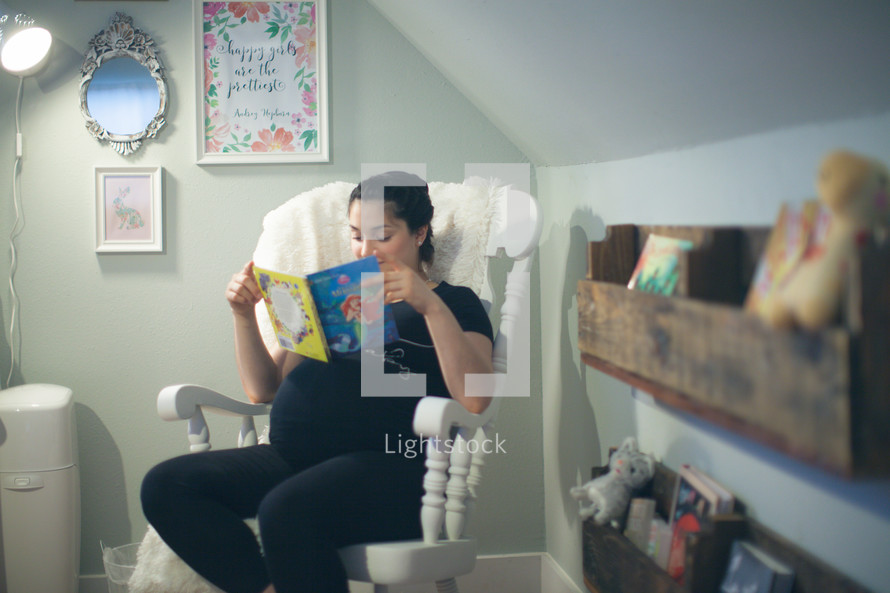 a pregnant woman reading a children's book in a nursery 