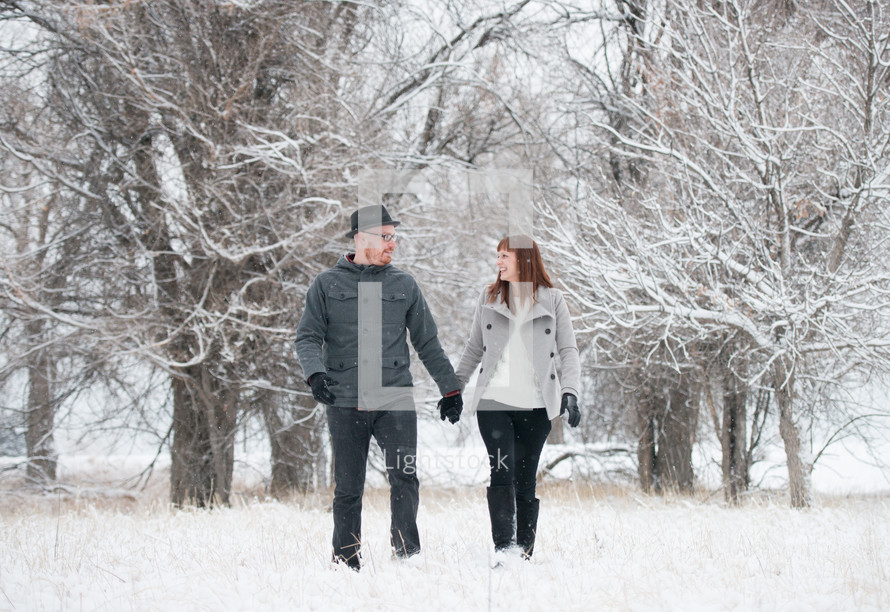 a couple holding hands walking in the snow 