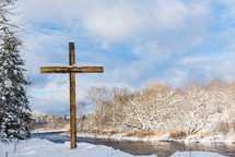 cross by a river in the snow 