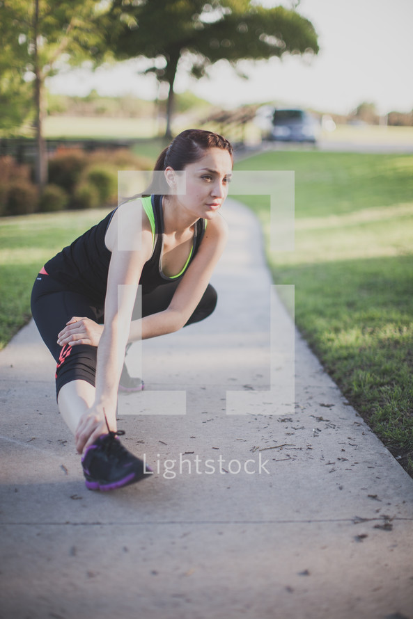 Woman stretching on the sidewalk before a run.