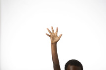 An African American boy with hand raised against a white background 