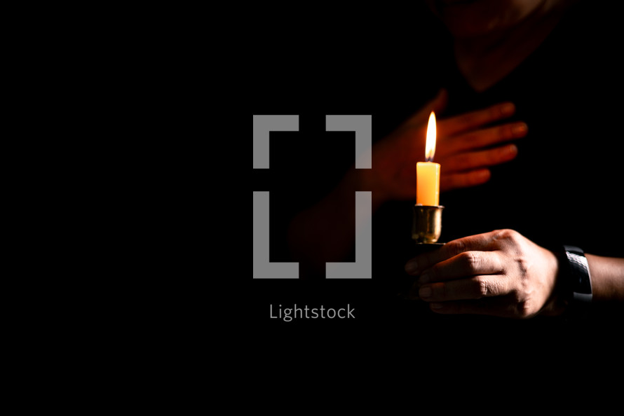 Bible and candlelight with praying hands