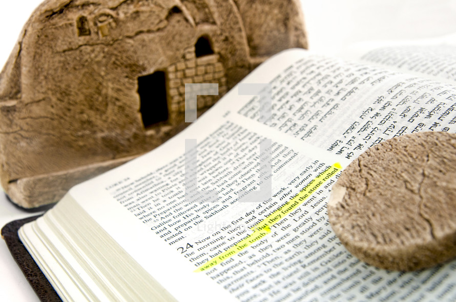 Bible open to The Gospel of Luke 24 in English and Hebrew with a Model of Jesus' Tomb and the stone which was rolled away.
