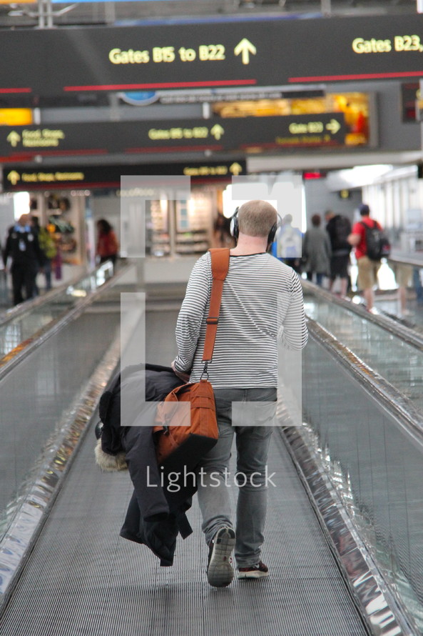 man carrying luggage on an airport travelator going on a journey  