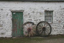 wagon wheels leaning against a house 