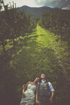 bride and groom lying down in an orchard 