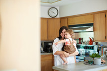 a mother holding her toddler daughter in the kitchen 